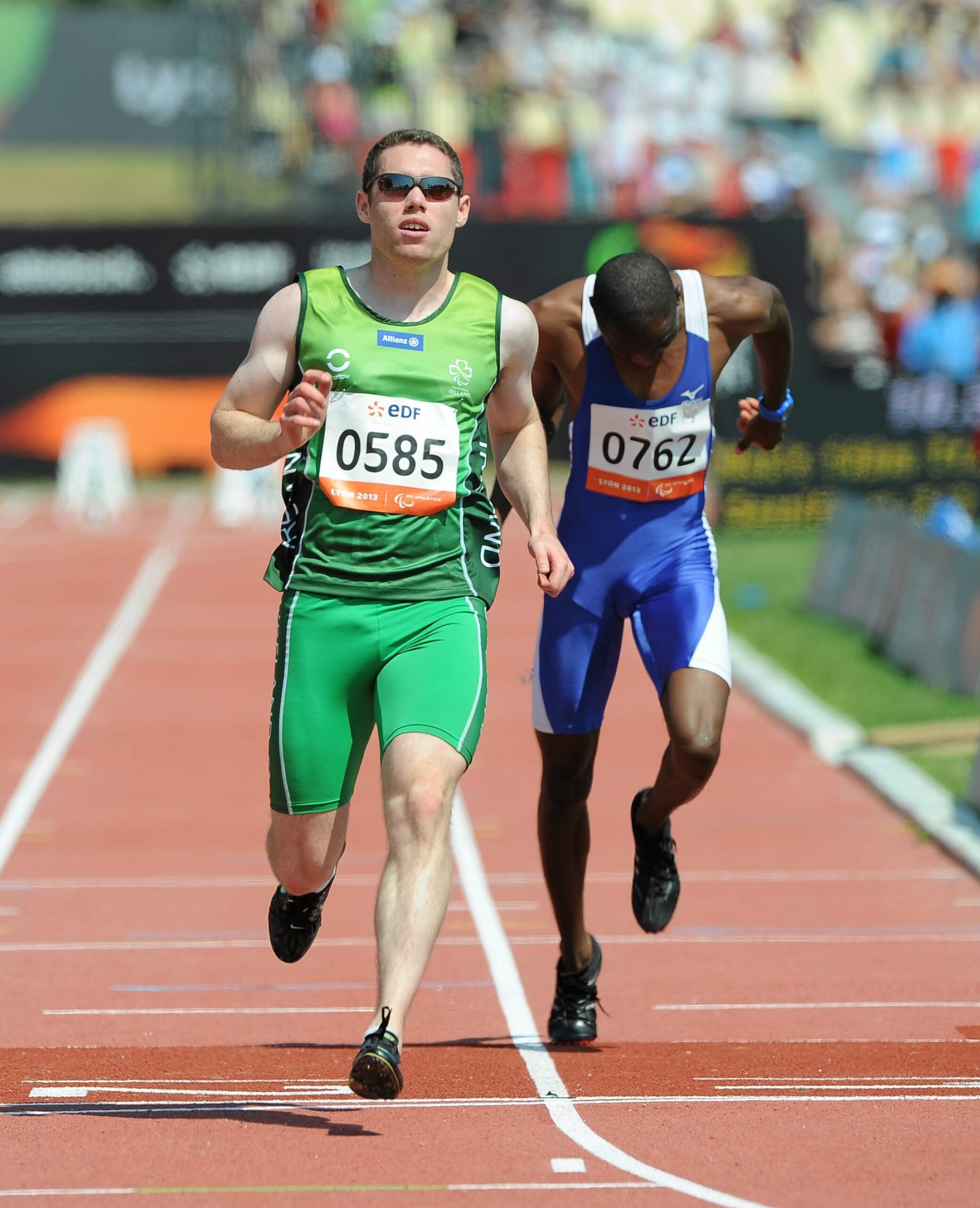 2 athletes running, one in green and one in blue. The athlete in green is ahead