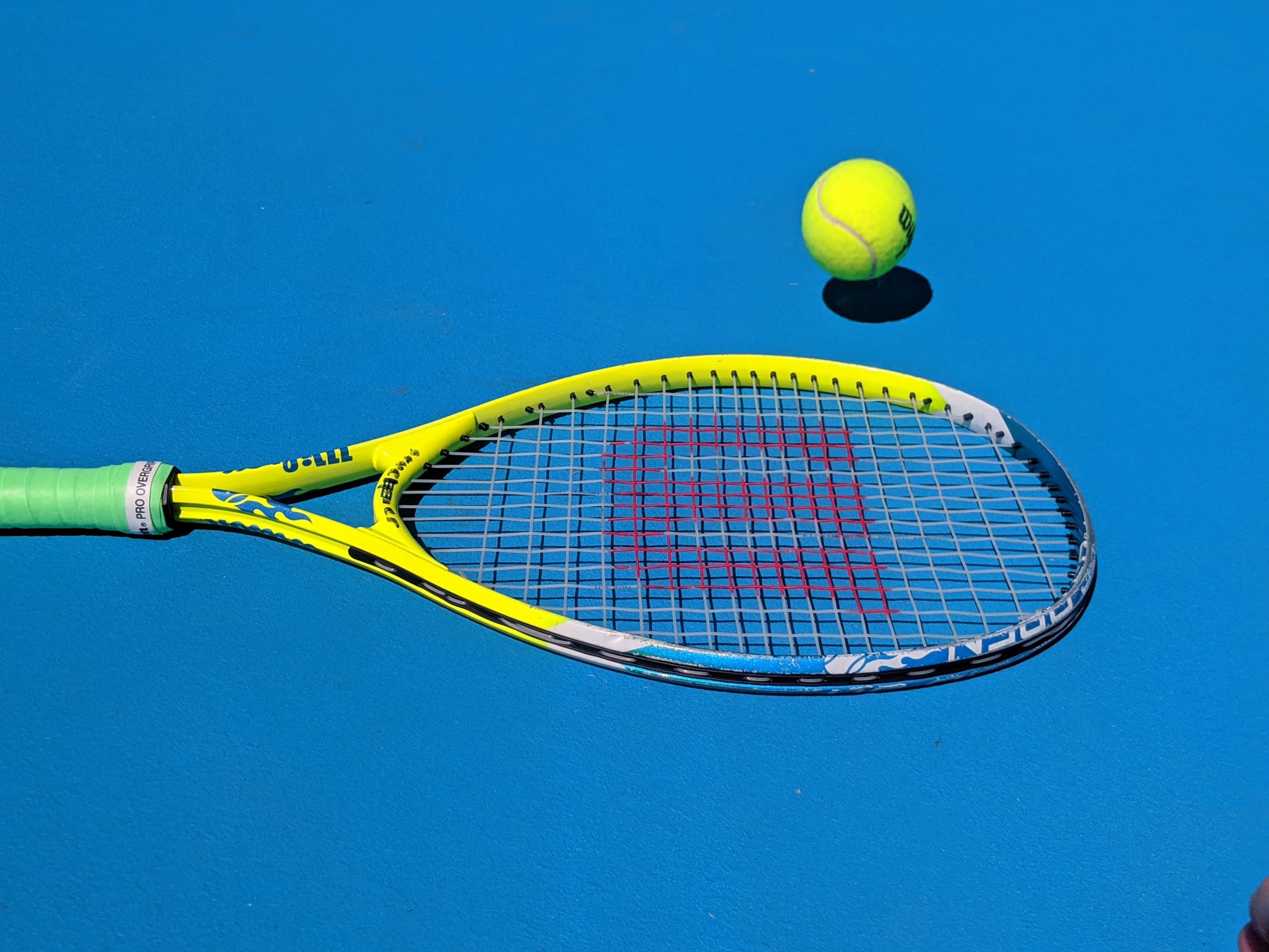 yellow and blue tennis racket hitting a yellow ball with a blue background
