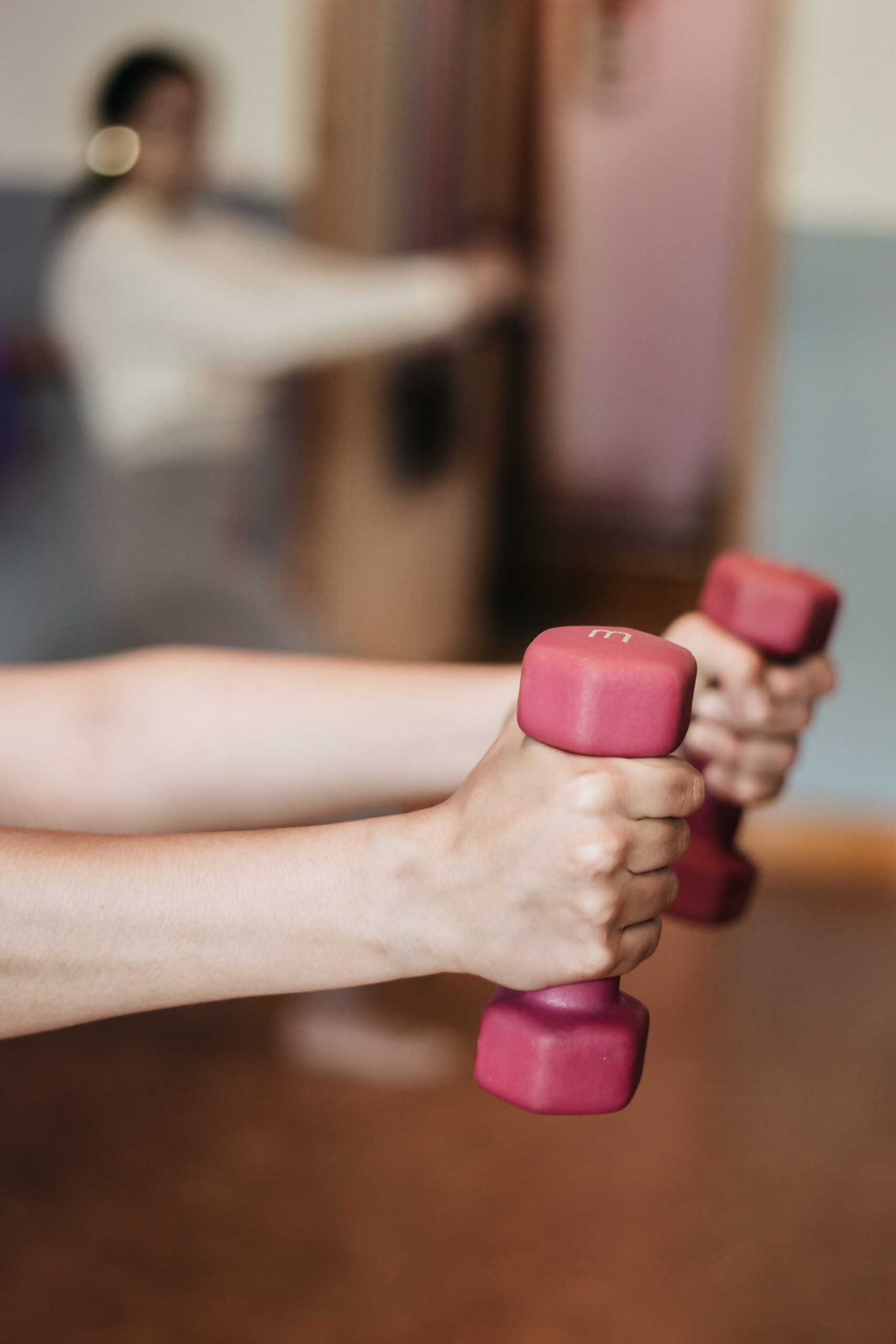 arms hold out two small pink dumbells