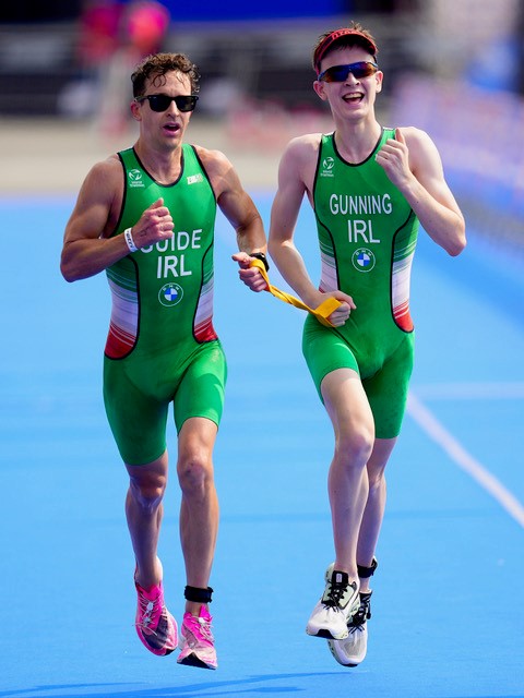 2 triathletes running, each holding one end of the tether