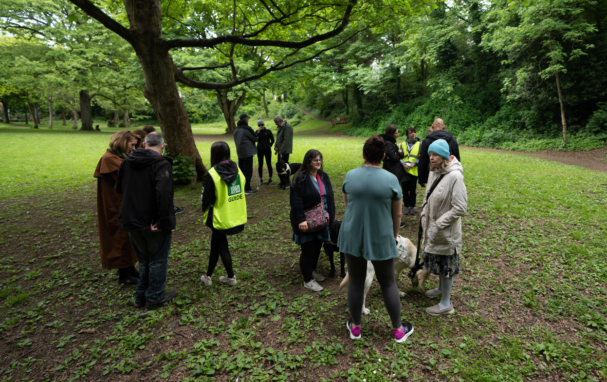 A group of participants standing under a tree speaking with each other.