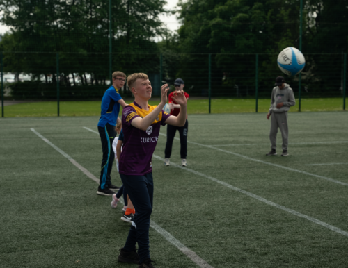 Participant with their arms in the air after throwing a rugby ball