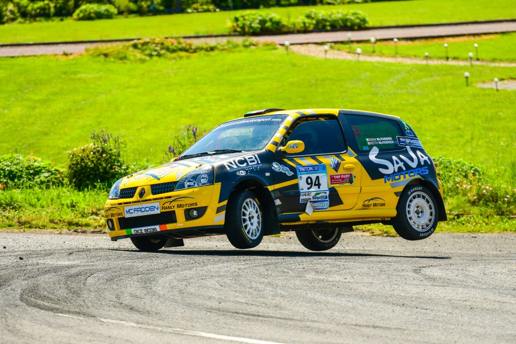 A yellow and blue rally car turning a corner on two wheels