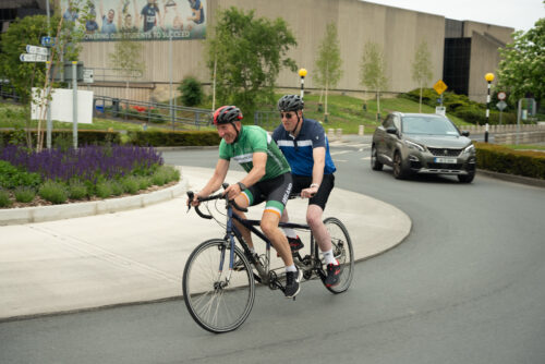 Pilot and a stoker going through a roundabout on their tandem bike.