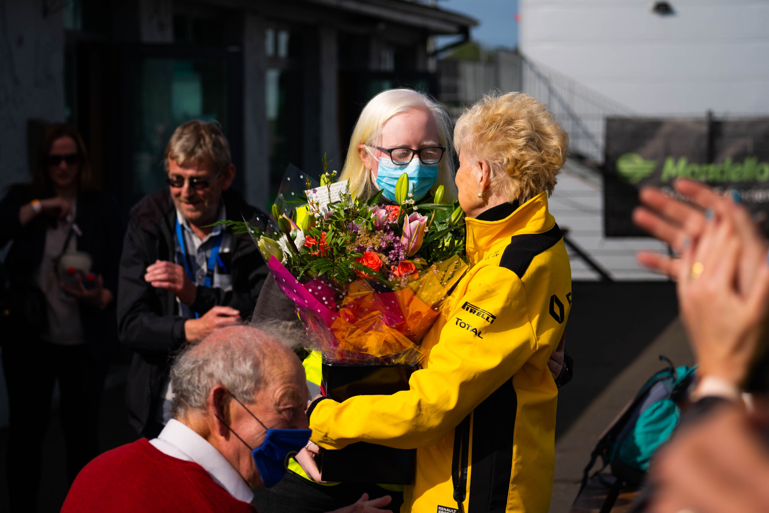 a female with white hair presenting a women with short hair with a bunch of flowers