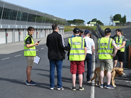 a group of participants and volunteers standing beside a race track