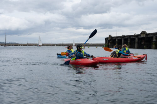participants in kayaks, one has their paddle up in the air