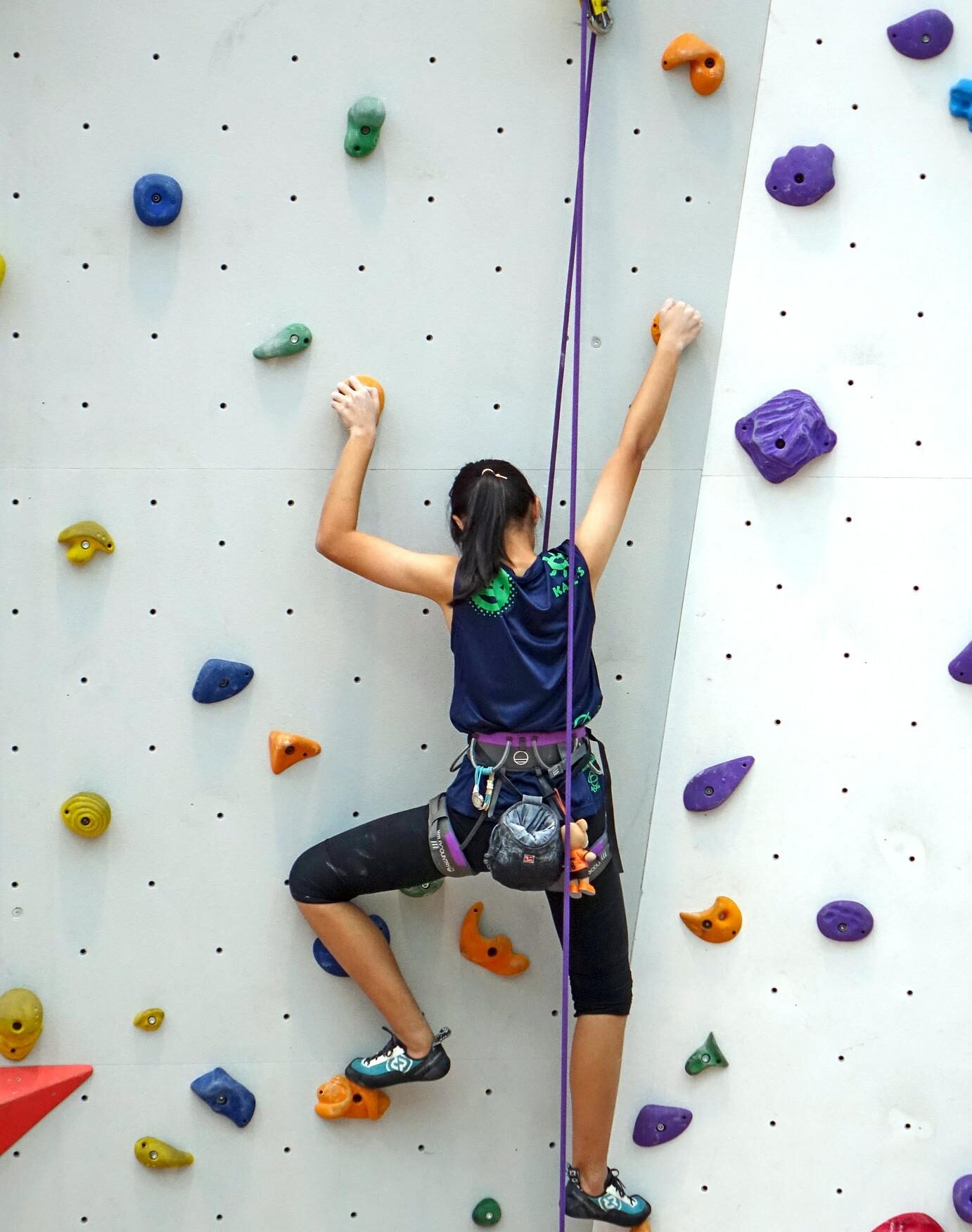 Photo of girl rock climbing on climbing wall.