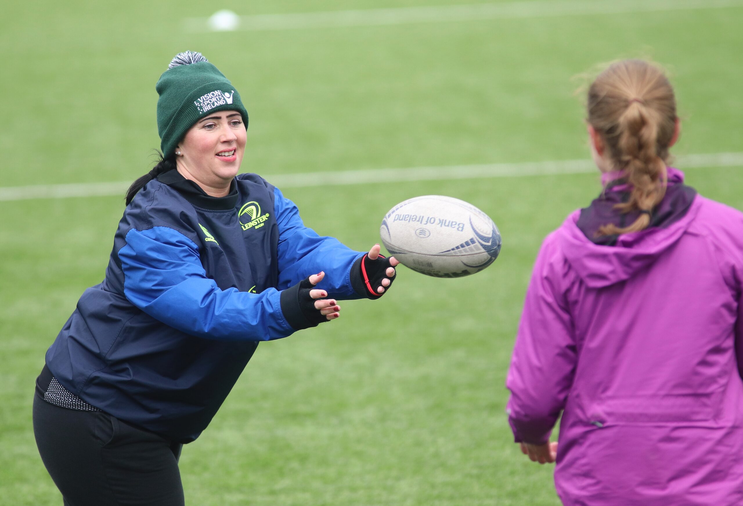 person throwing rugby ball to another female participant