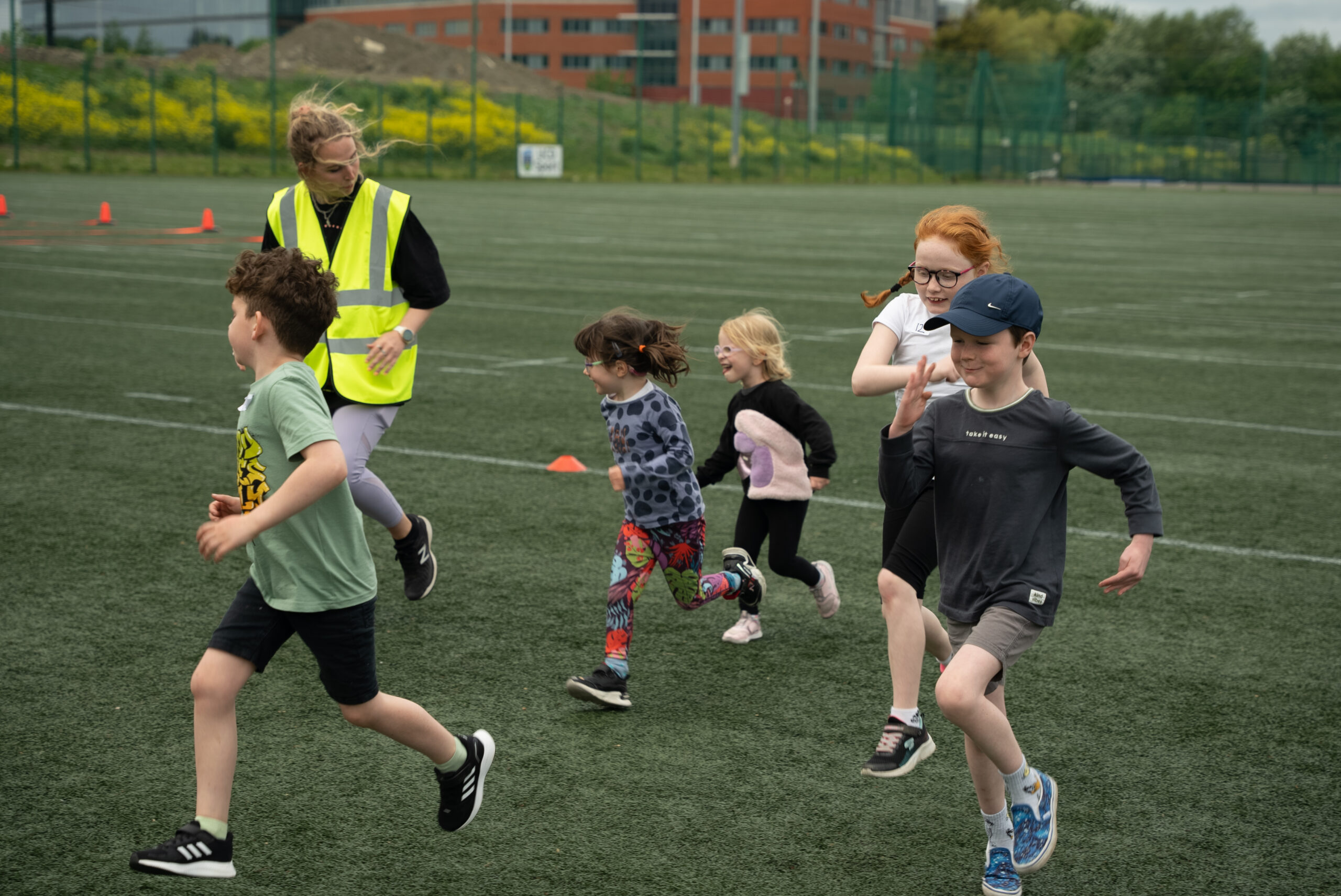 photo of six kids, three boys and three girls running on a rugby pitch