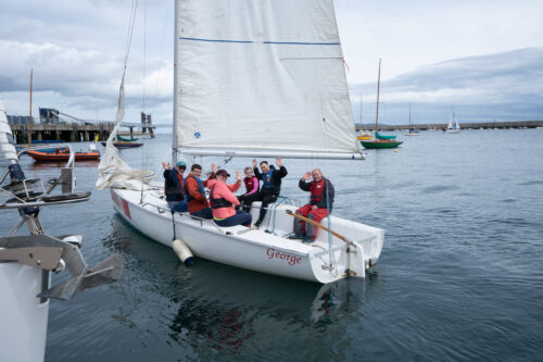 photo of a group of seven people, a mixture of adults and kids on a sailing boat