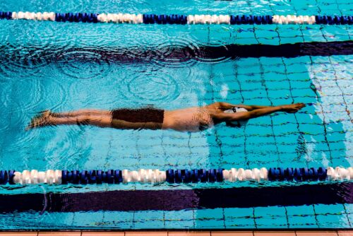 Photo from above of a person swimming in a pool lane