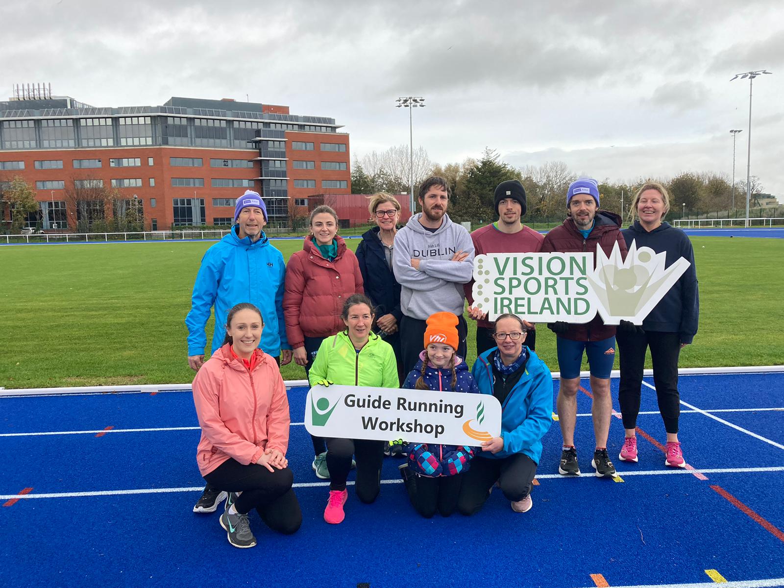 Guide Running workshop attendee's posing with Guide Running Workshop sign in UCD Athletics track.
