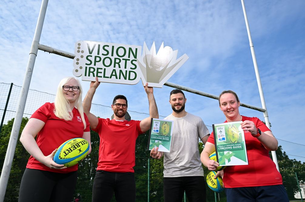 A group photo of Ian Mc Kinley Robbie Henshaw and 2 female VI rugby players holding rugby balls coaching guides and a Vision Sports Ireland logo sign