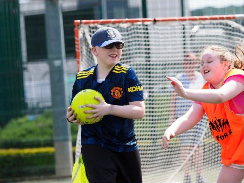 a child holds a football during a GAA coaching session