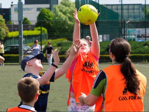 a child jumps to catch a football during a GAA coaching session