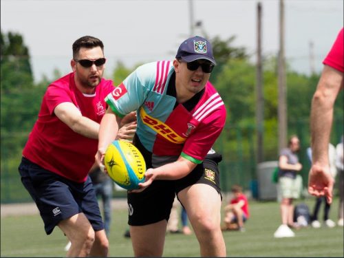 a Harlequin player is about to pass the ball while being chased by an Irish vi rugby player