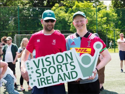 An Irish player and a Harlequins player hold up a Vision Sports Ireland sign after a vi rugby game