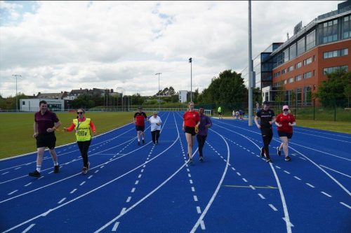 Participants and guides running down an athletics track