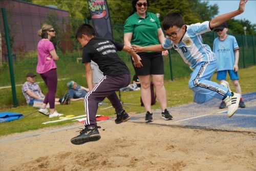Two boys, mid-air, in a long jump