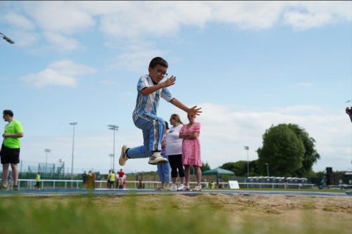 A boy about to land in a long jump