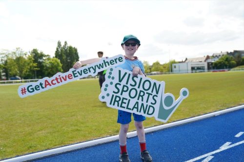 A child holding up a Vision Sports Ireland sign and a #GetActiveEverywhere sign