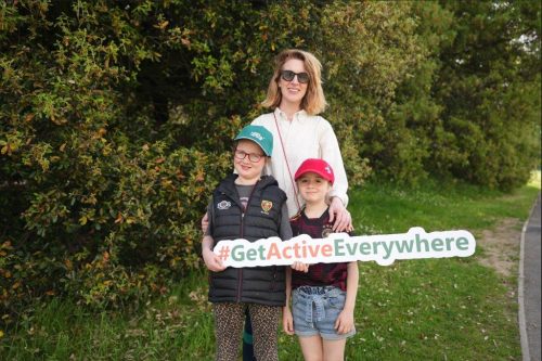 A mother and two daughters holding a #GetActiveEverywhere sign