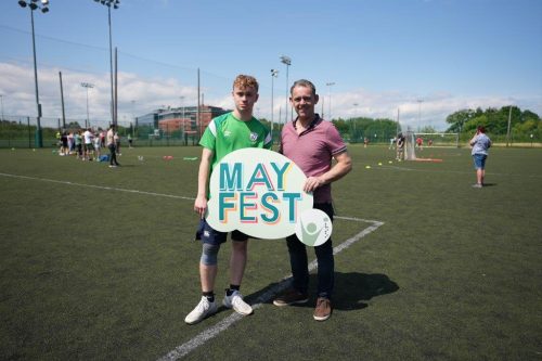A dad and son hold up a MayFest sign