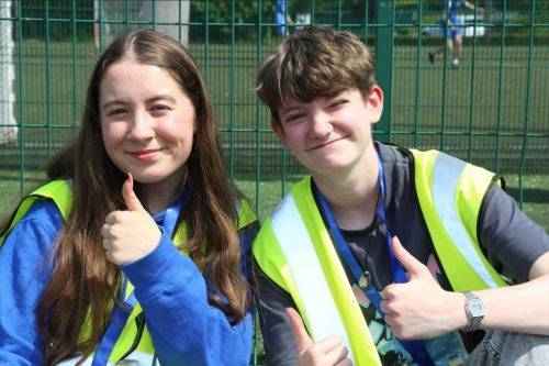 Two volunteers smiling with their thumbs up