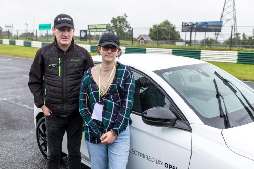 A participant and a driving instructor stand outside a car after driving around the track at #ZeroLimits23