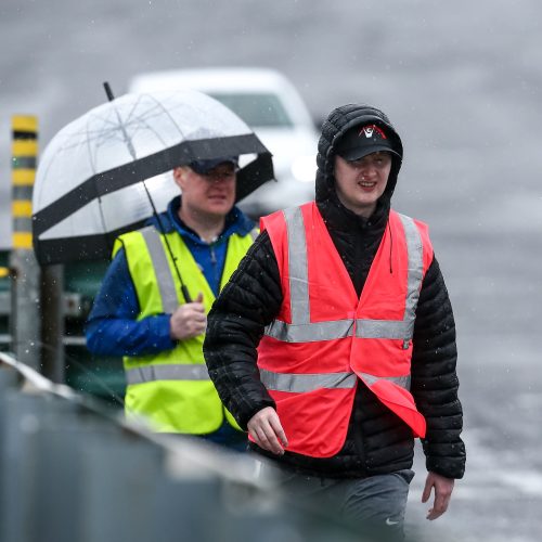 a volunteer and staff member walking in the rain on the side of the track