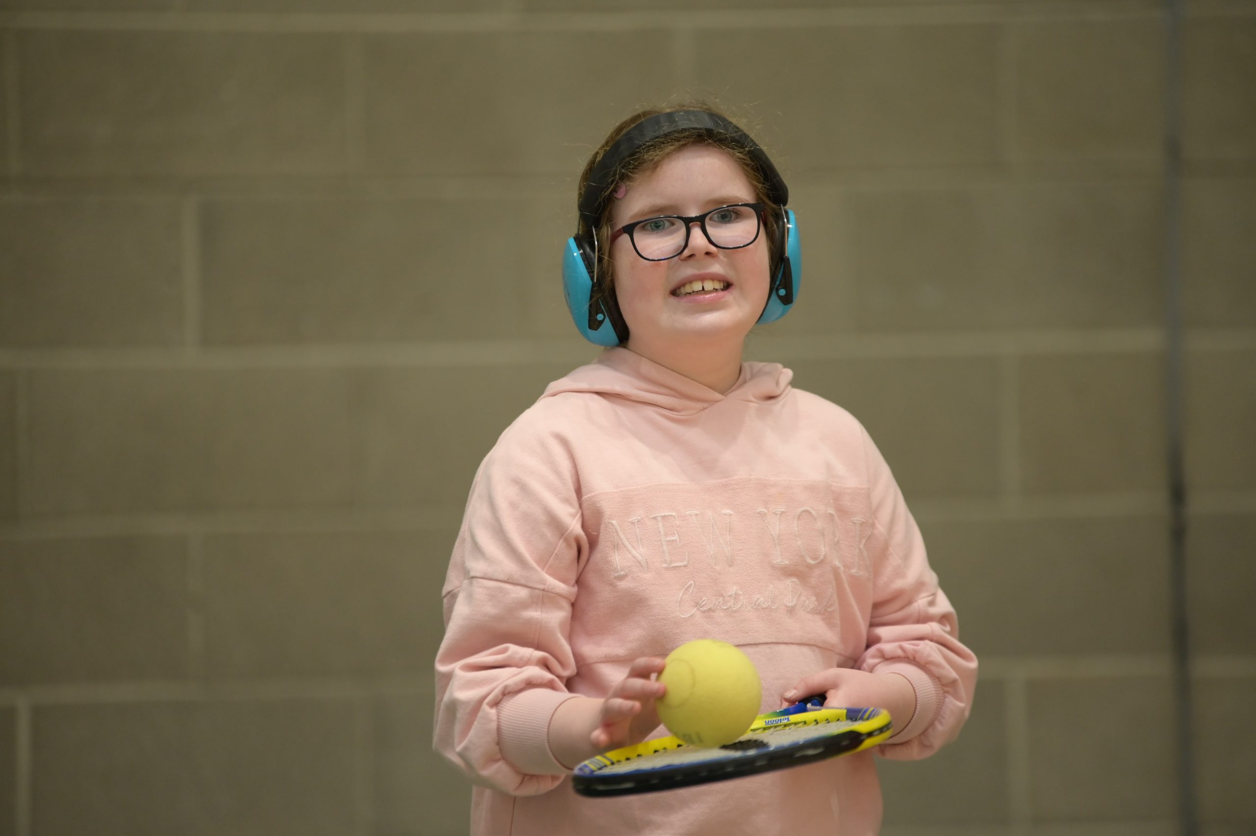 Young girl with a tennis ball on her racket.