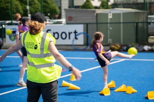 a young participant kicks a football during a GAA session