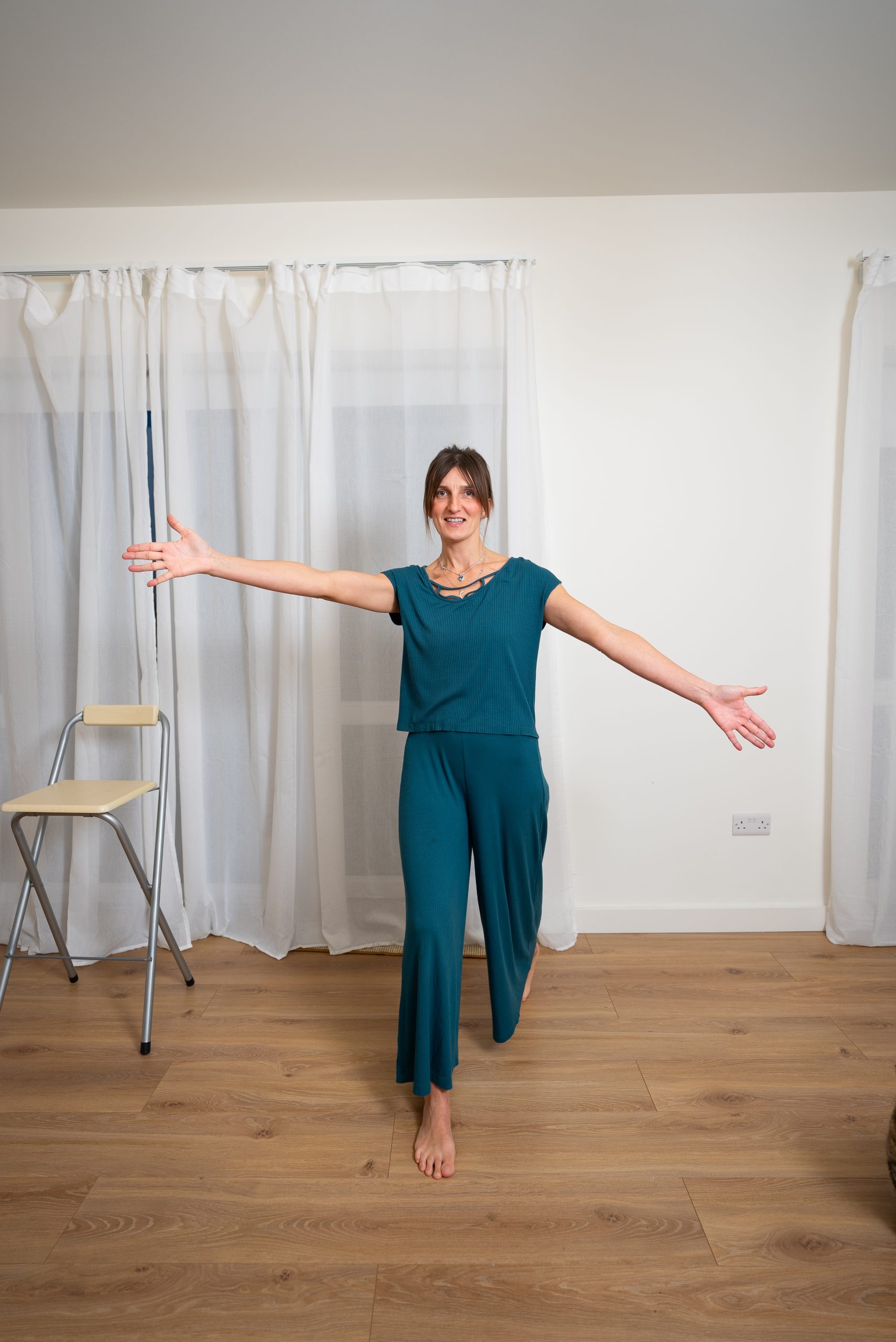Movement instructor Gita stands with her arms out stretched during a movement class in her home